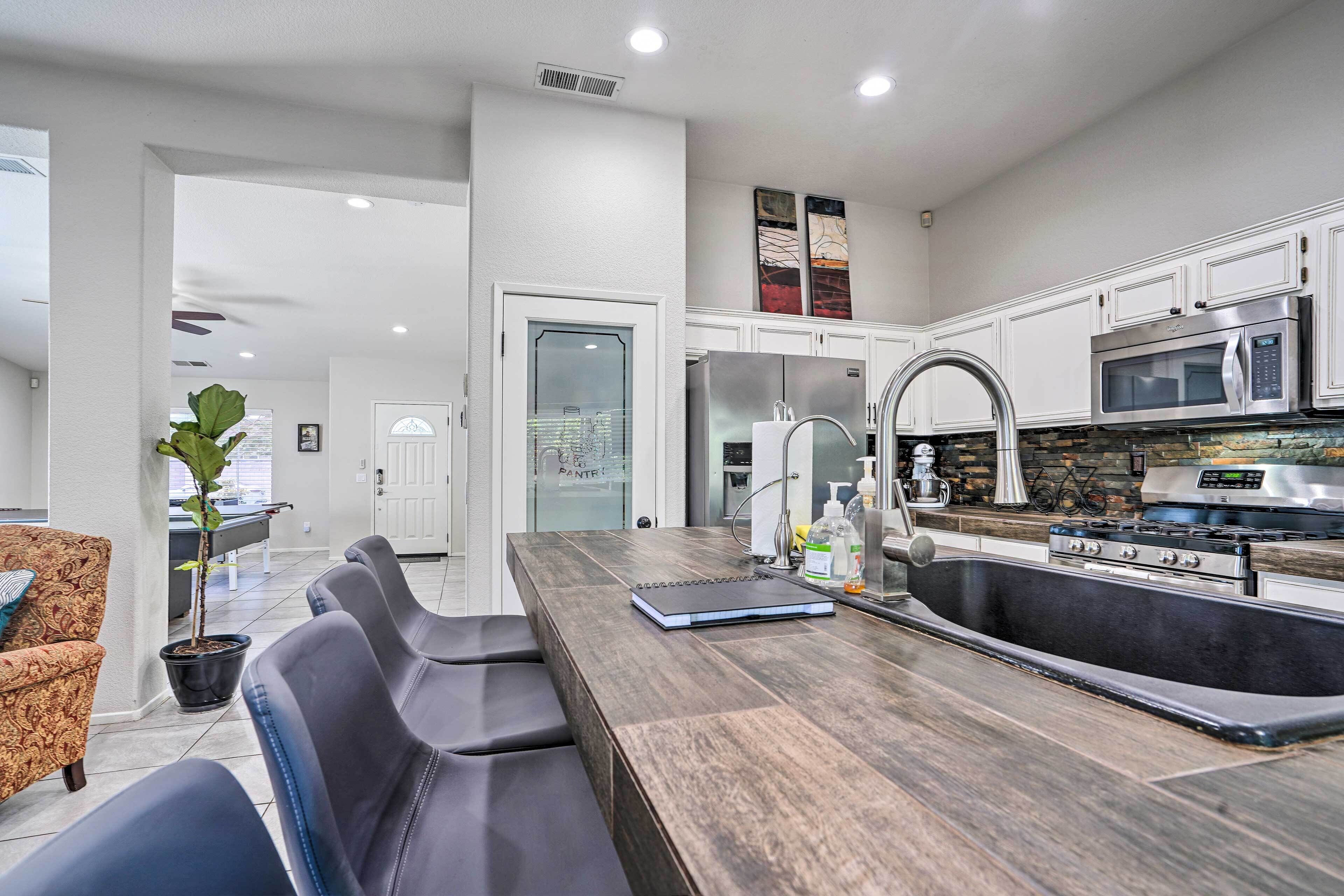 A modern kitchen with white cabinets, stainless steel appliances, a large island with seating, and a view into the dining area.