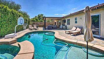 A backyard with a swimming pool, a basketball hoop, and outdoor seating.