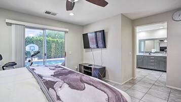 Un dormitorio con una cama grande, un ventilador de techo, un televisor y vistas al exterior.