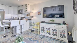Una cocina moderna con armarios blancos, una barra con taburetes, microondas y ventilador de techo.
