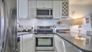 Una cocina moderna con armarios blancos, electrodomésticos de acero inoxidable y encimera de granito.