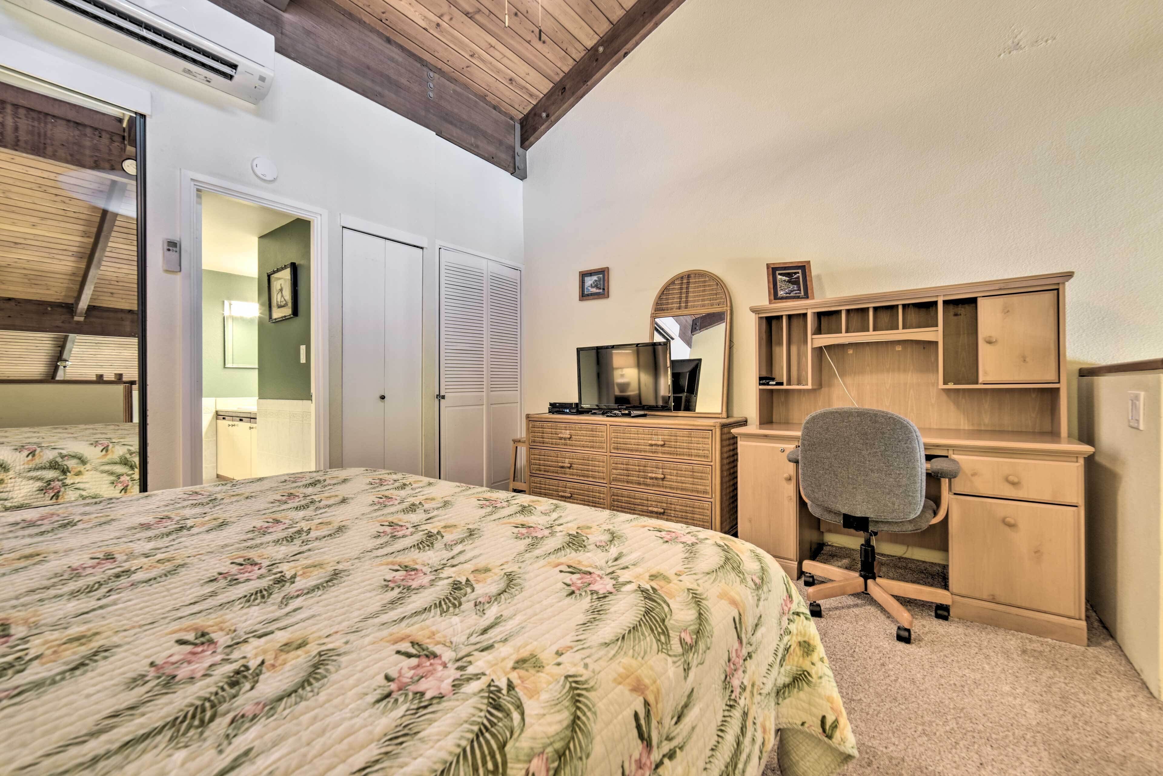 A bedroom with a bed, a desk, and a chair. There is a wardrobe and a mirror on the wall.