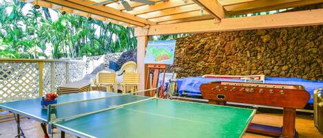 Une table de ping-pong, une table de baby-foot et un espace détente avec des chaises et une table.
