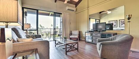 A spacious living room with a wooden ceiling, large windows, and a balcony.