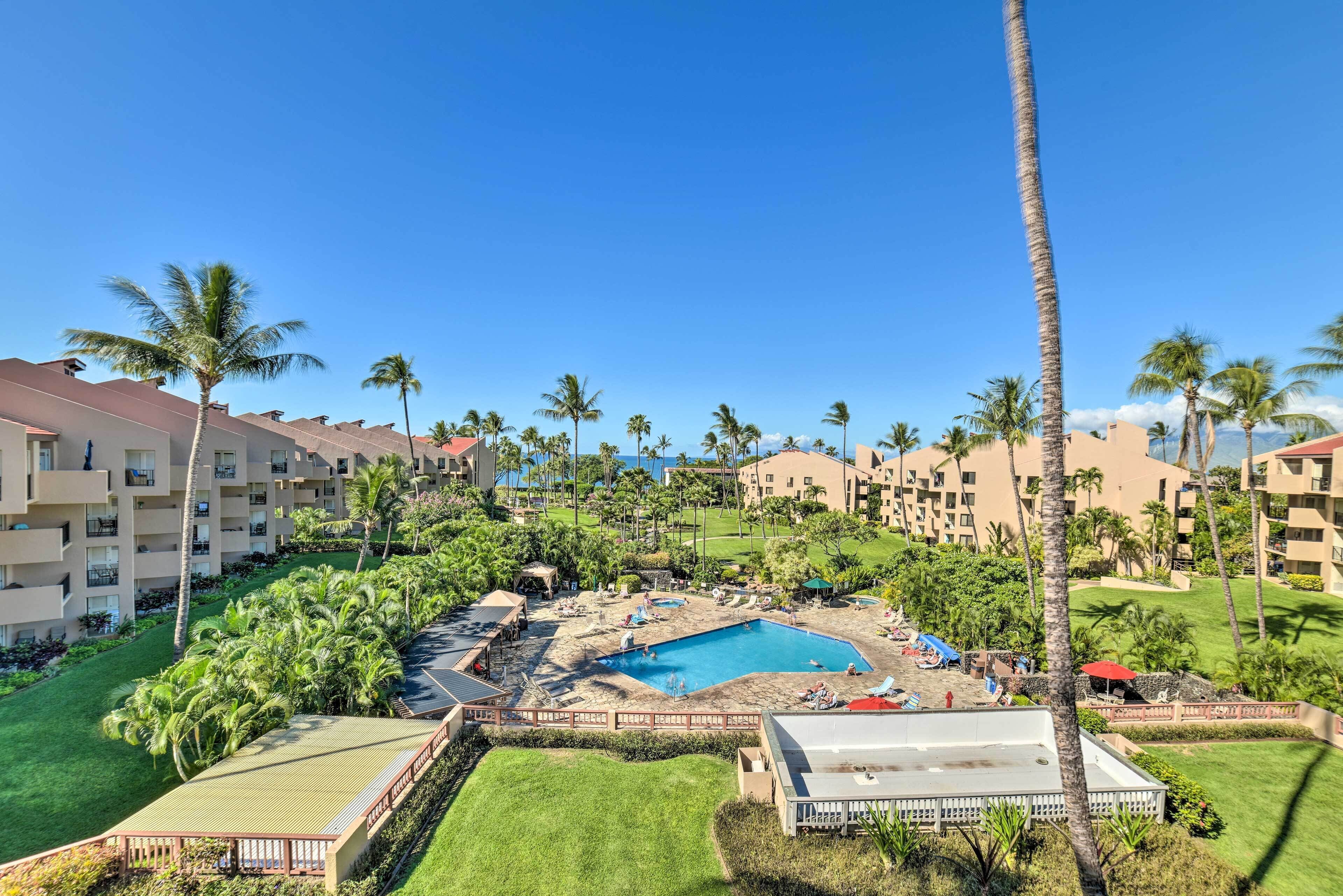 A resort with multiple buildings, a central pool area, and surrounding palm trees.