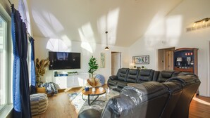 A spacious living room with a large leather sofa, a flat-screen TV, and a wooden coffee table. - Lake View Cottage: Lake Ozarks Getaway (Gravois Mills)