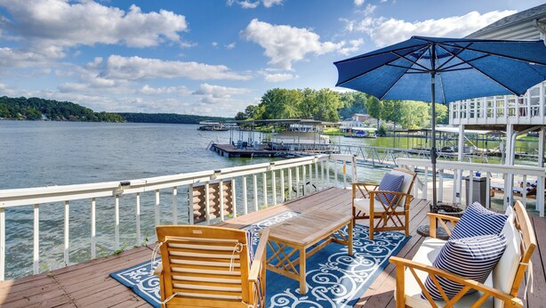A deck with wooden furniture, a blue patterned rug, and a large umbrella. - Lake View Cottage: Lake Ozarks Getaway (Gravois Mills)