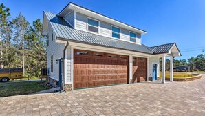 A two-story house with a large garage and a covered porch. - East Bay Vacation Rental w/ Dock! (Gulf Breeze)