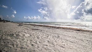 Een zandstrand met golven en een heldere lucht.