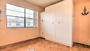 Een kamer met een groot raam, een witte kast en een betegelde vloer.