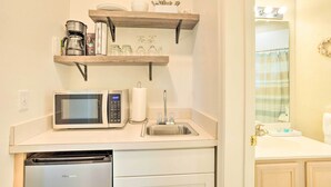 Cocina compacta con microondas, cafetera y lavabo.