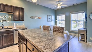 A kitchen with dark wood cabinets, a granite countertop, and a ceiling fan. - Dtwn Ludington Condo: Balcony, Walk To Beach! (Ludington)