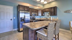 A kitchen with dark wooden cabinets, stainless steel appliances, and a granite countertop. - Dtwn Ludington Condo: Balcony, Walk To Beach! (Ludington)