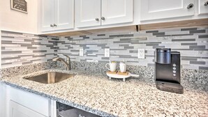 A kitchen with white cabinets, a granite countertop, a stainless steel sink, and a coffee maker. - Orlando Family Condo ~ 9 Mi to Magic Kingdom! (Orlando)