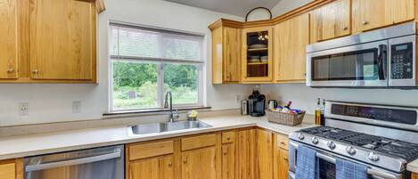 A kitchen with wooden cabinets, a stainless steel dishwasher, a double oven, and a microwave.