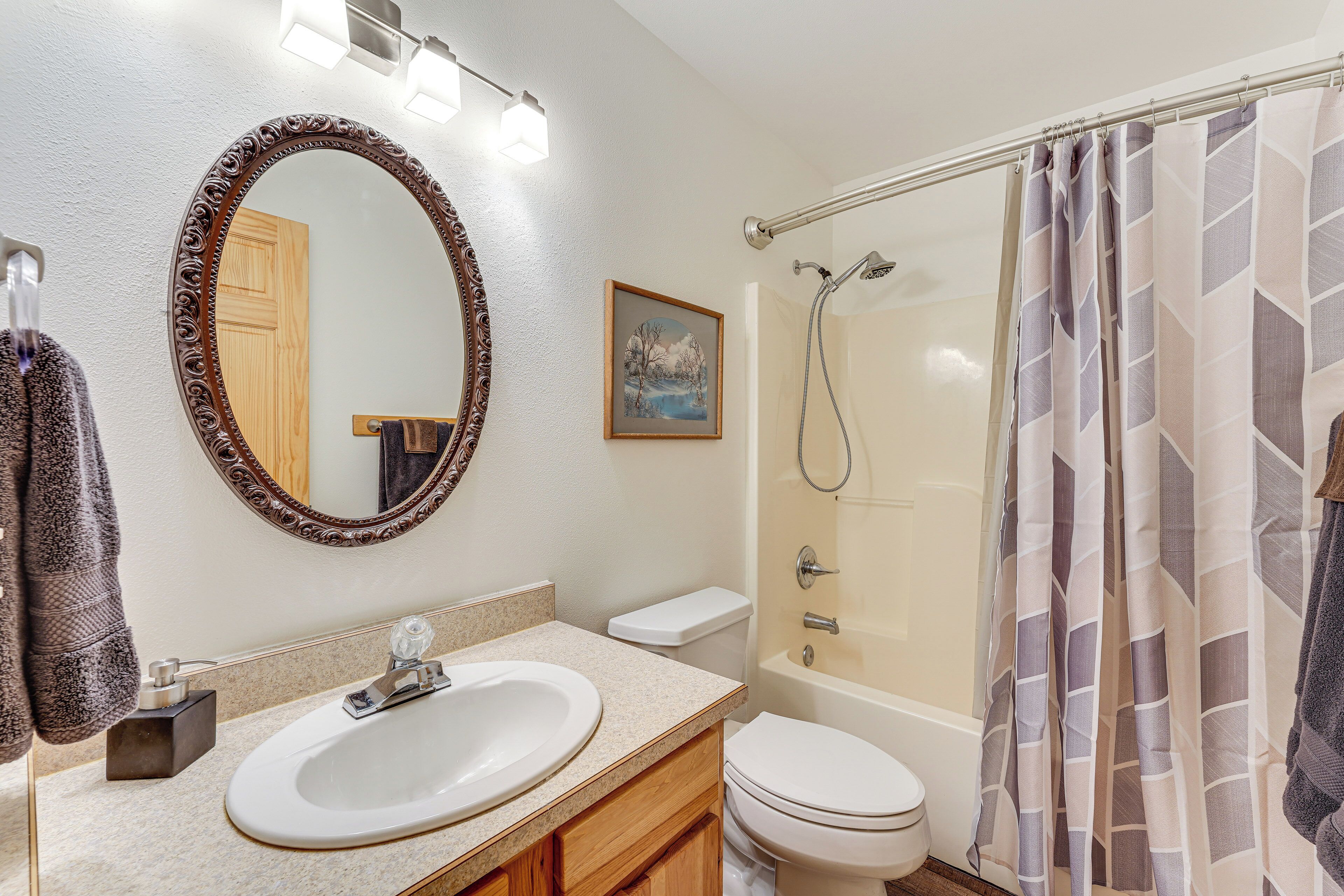 A bathroom with a round mirror, a sink, a toilet, and a shower.