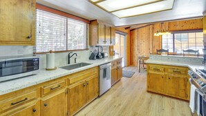Una cocina con armarios de madera, microondas, fregadero y estufa.