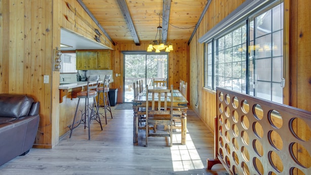 Interior de una cabaña de madera con comedor, cocina y zona de estar.