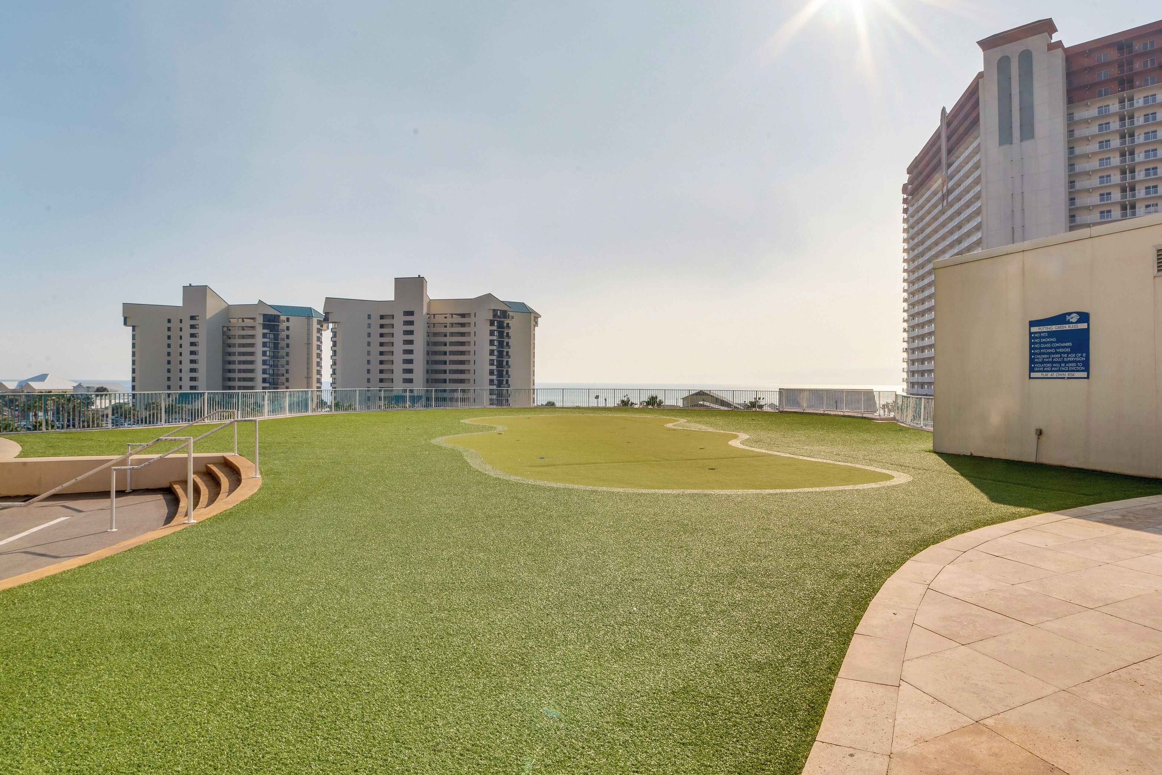 Une terrasse avec un revêtement d’herbe artificielle, un chemin sinueux et une vue sur les gratte-ciel.