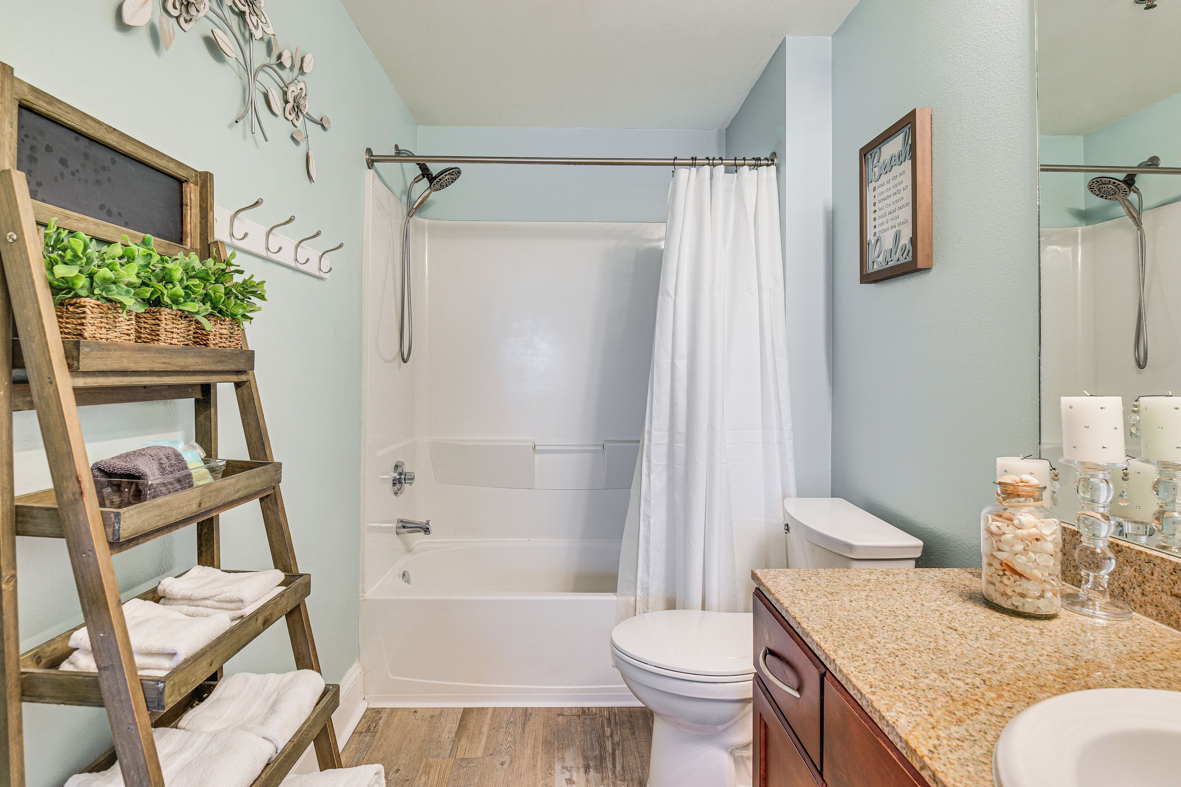 A bathroom with a shower, toilet, and a wooden shelf with towels.