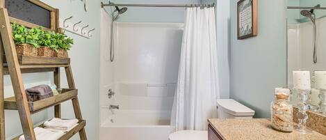 A bathroom with a shower, toilet, and a wooden shelf with towels.