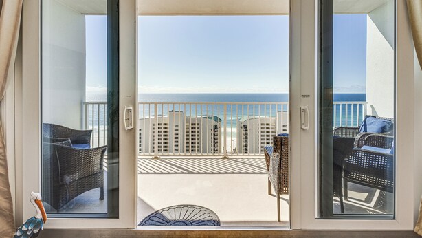 A balcony with a view of the ocean and a building in the background.