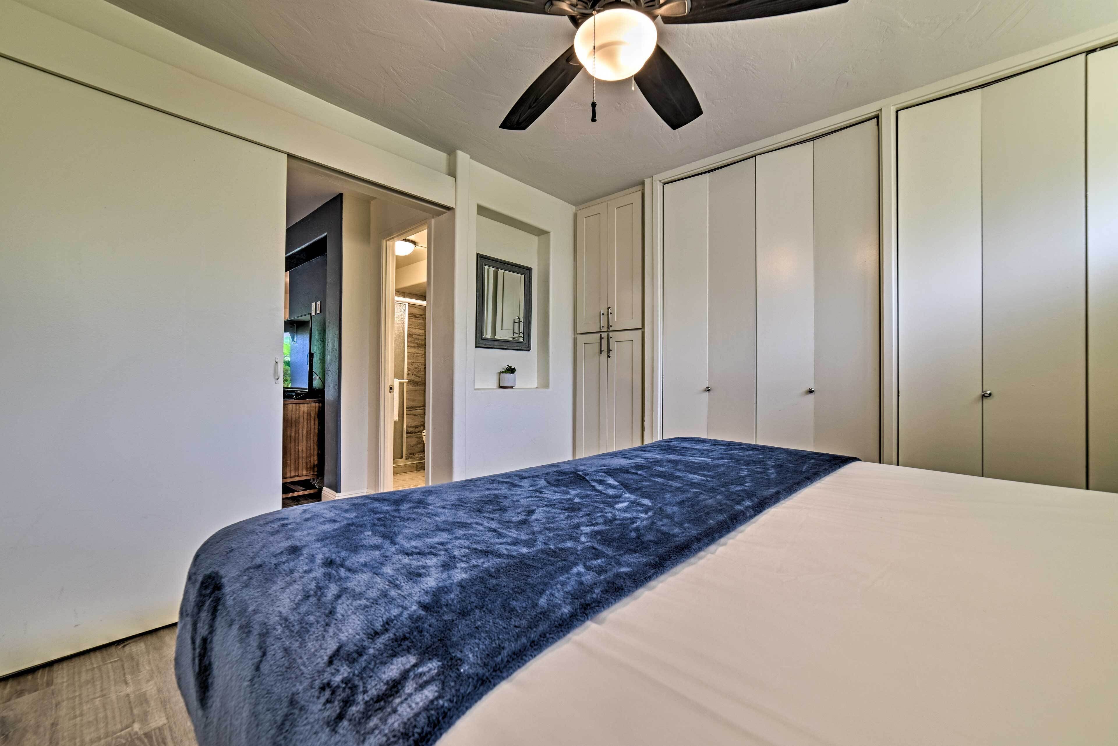 A bedroom with a bed, a ceiling fan, and a wardrobe.