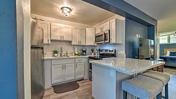 A modern kitchen with white cabinets, a granite countertop, and stainless steel appliances.