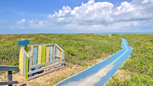 A beach with a wooden boardwalk leading to a sign labeled "Aquarium."