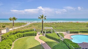 A resort with a swimming pool, palm trees, and a view of the beach.