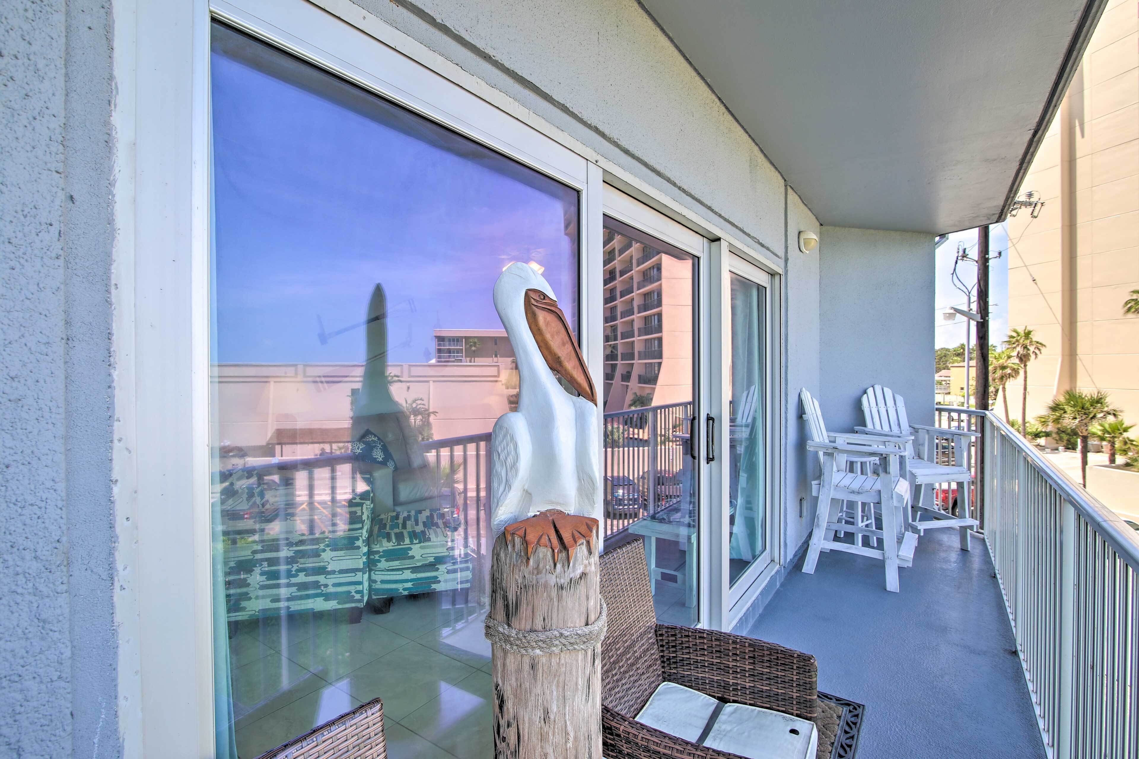 A balcony with wicker furniture, a wooden post, and a glass door leading to a building.
