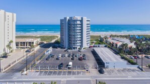 A high-rise hotel with a parking lot and ocean view.