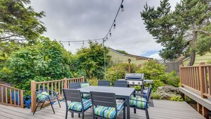 Une terrasse extérieure avec une table et des chaises pour les repas, un barbecue et des guirlandes lumineuses.
