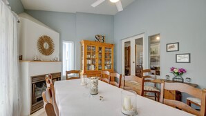 Une salle à manger avec une longue table, des chaises en bois, un buffet aux portes vitrées et une cheminée.