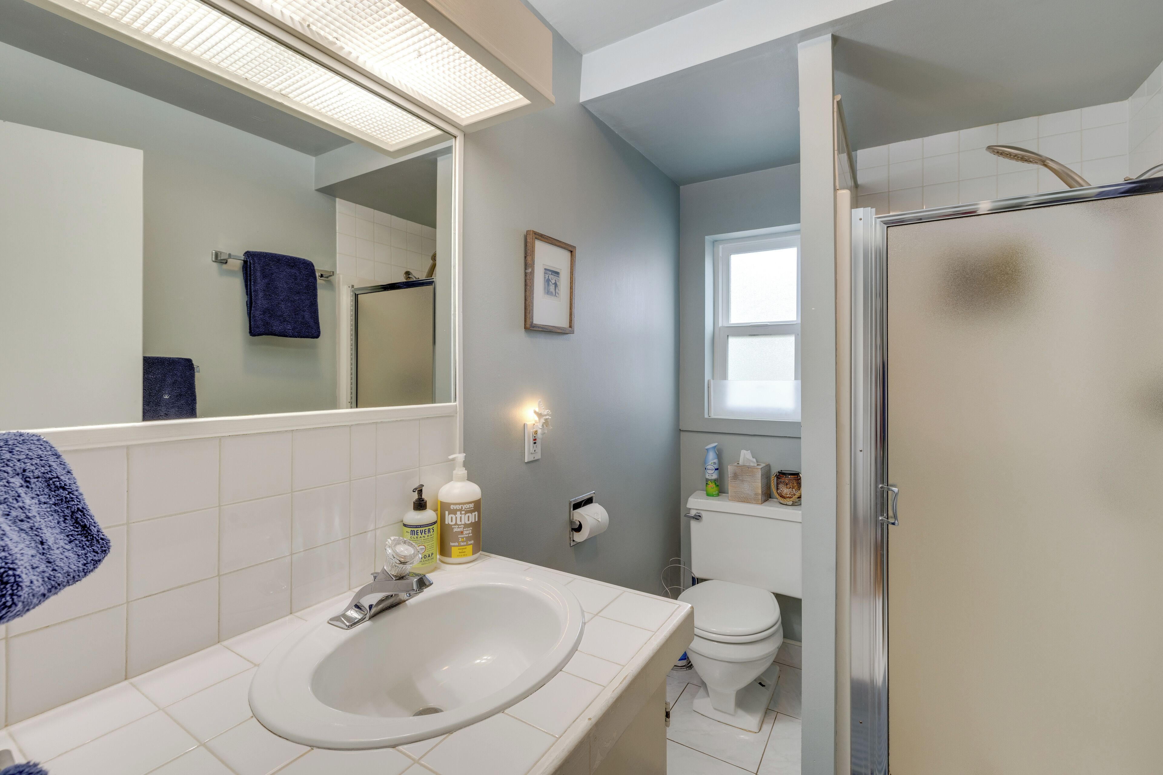 A bathroom with a white sink, a mirror, a toilet, and a shower area.