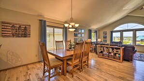 A spacious living room with a wooden dining table, chairs, and a chandelier. There is a large window with a view of the outdoors. - Pagosa Springs Home w/ Deck & Grill, Walk to Town! (Pagosa Springs)