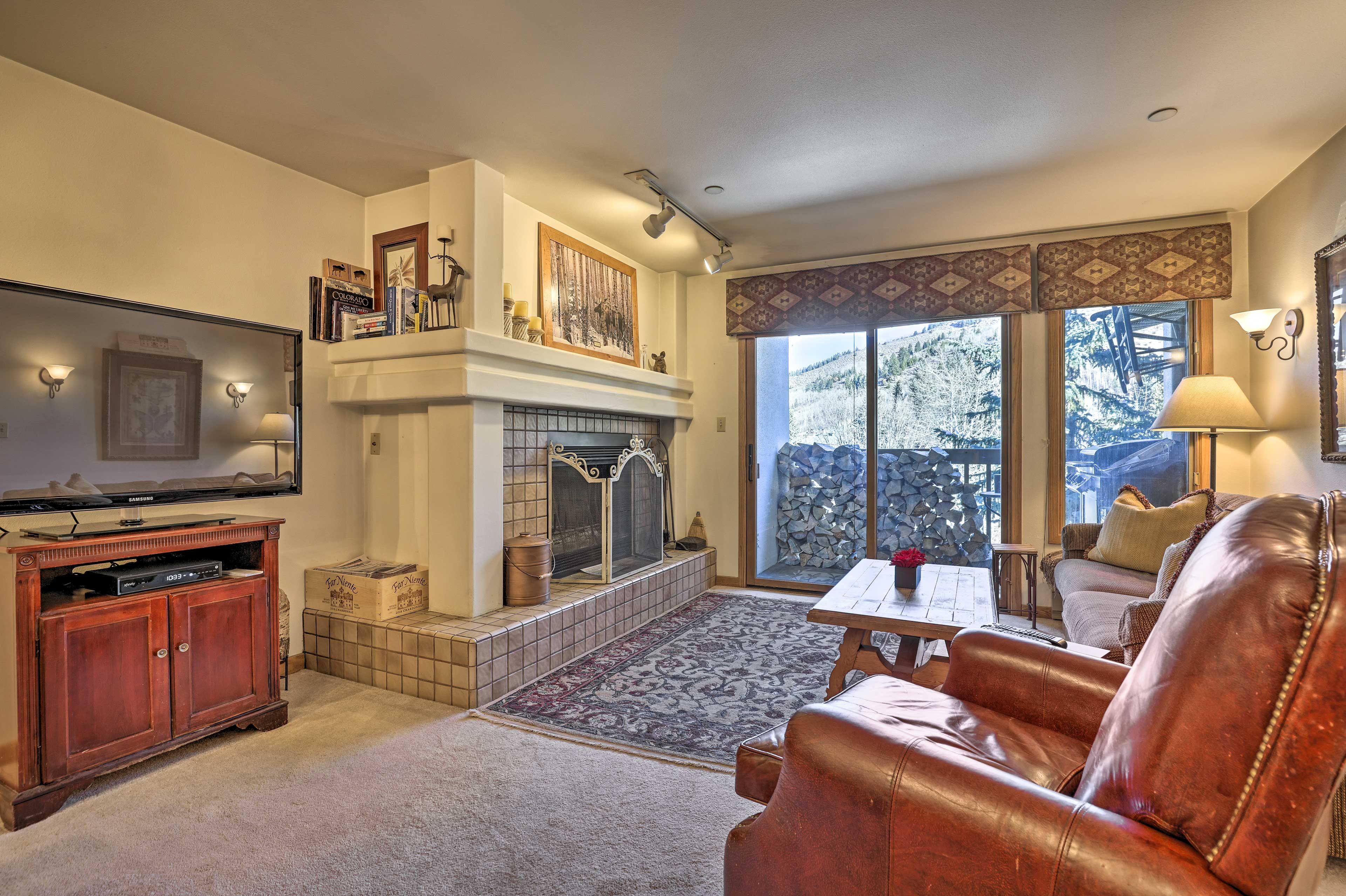 Una sala de estar con chimenea, televisor y sofá de cuero.