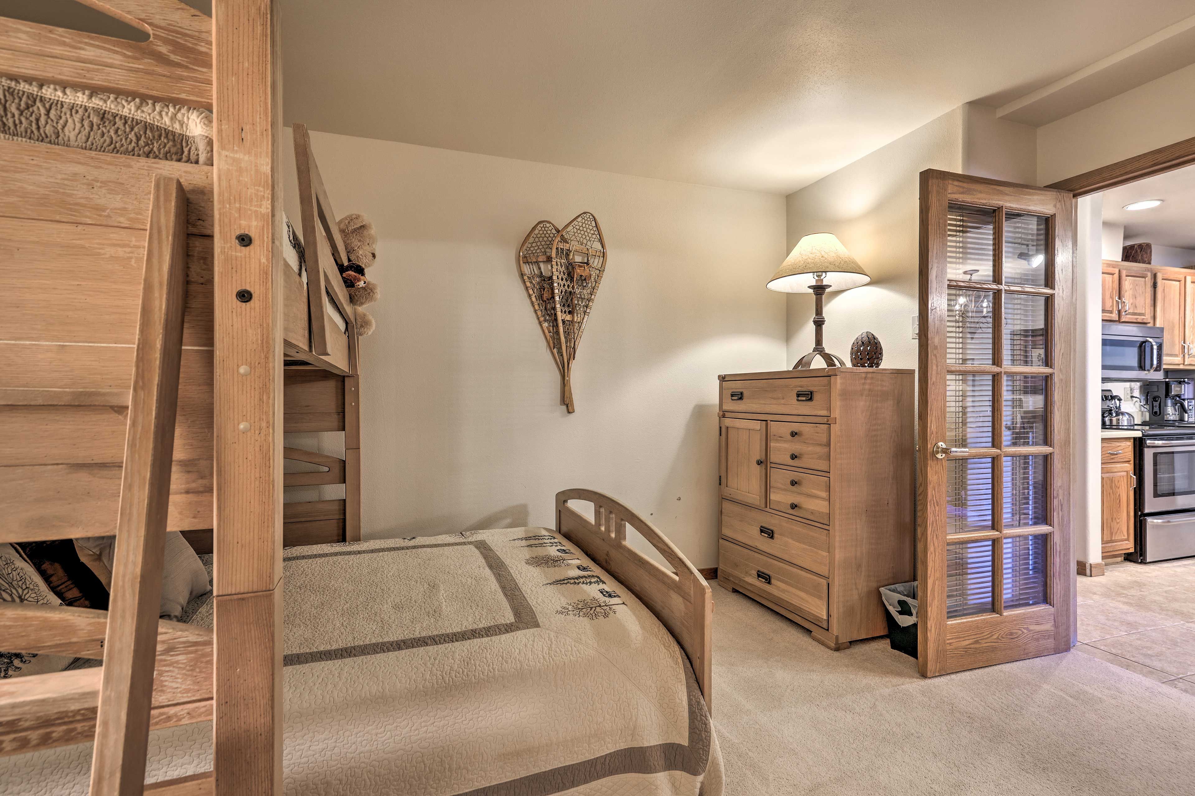 Una camera da letto con un letto di legno, una cassettiera, un comodino e un elemento decorativo a parete.