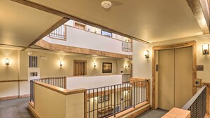 Un intérieur à plusieurs niveaux, avec des rampes en bois, un escalier et une vue sur l’extérieur.