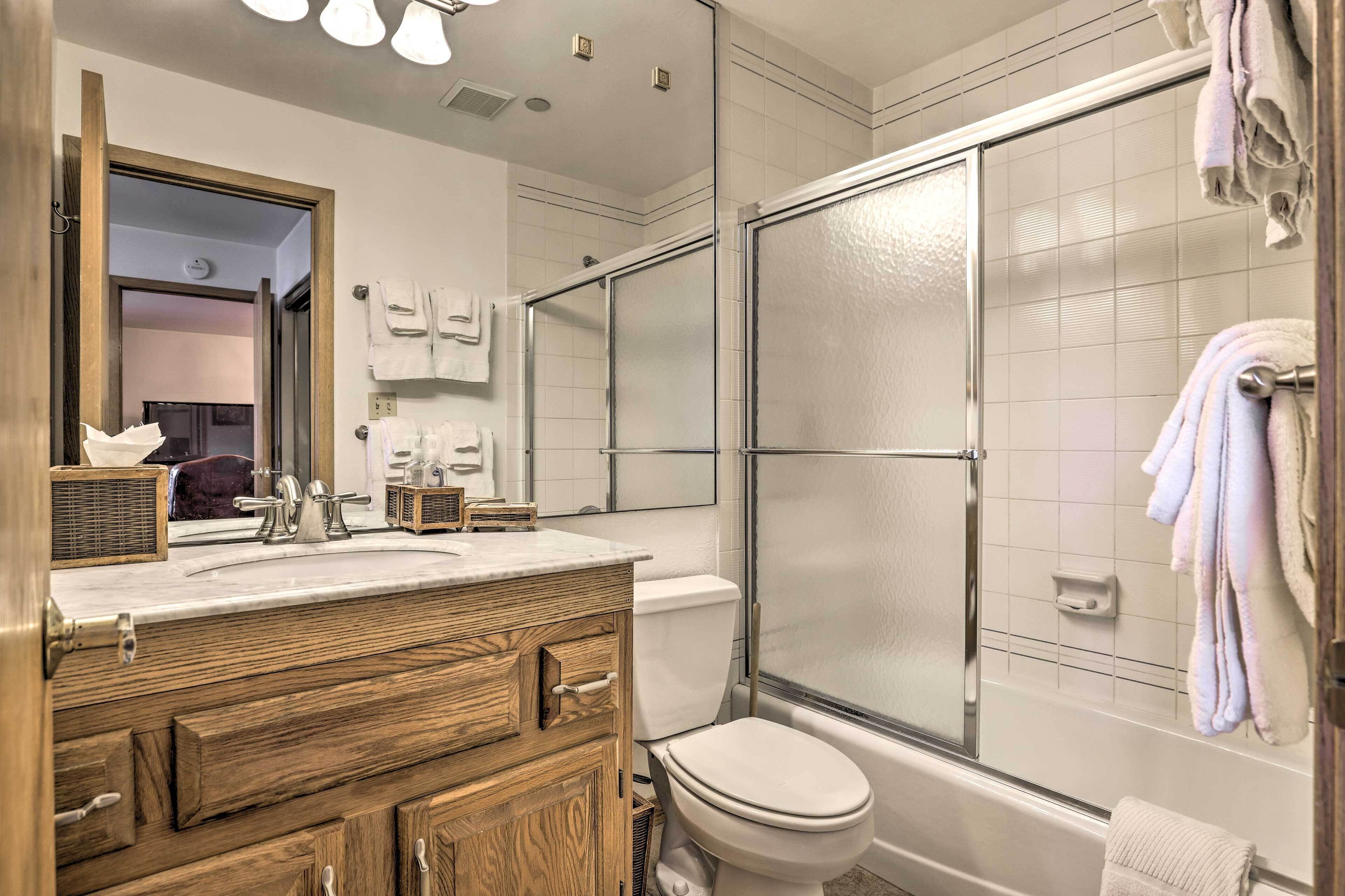 Un bagno con un mobile lavabo in legno, un water, cabina doccia in vetro e uno specchio.