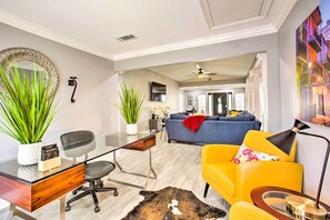 A modern living room with a glass desk, a sofa, and a yellow armchair. - Vibrant Terrytown Home w/ Yard ~ 6 Mi to Nola (Gretna)