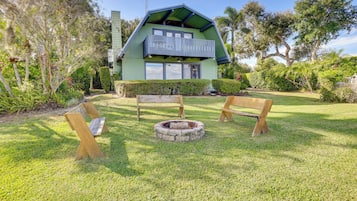 A house with a green roof, a balcony, and a fire pit in the yard.