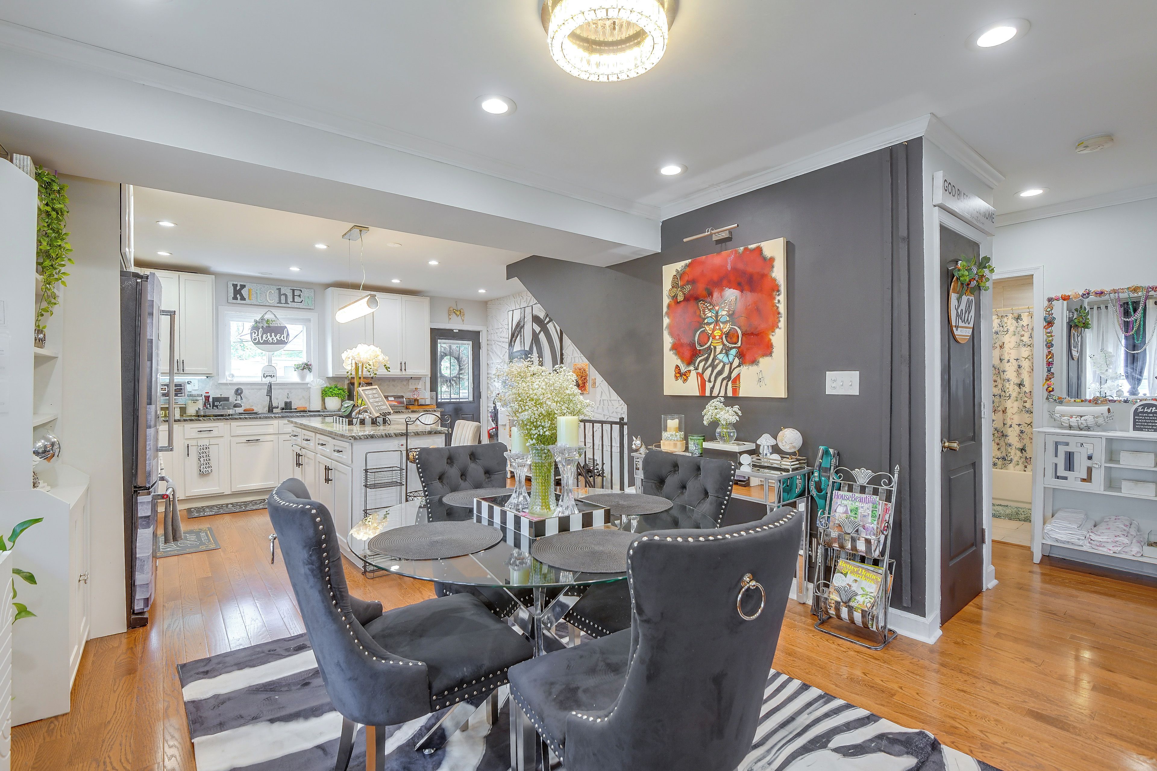 A modern living room with a dining area, kitchen in the background, and a staircase leading to another level.