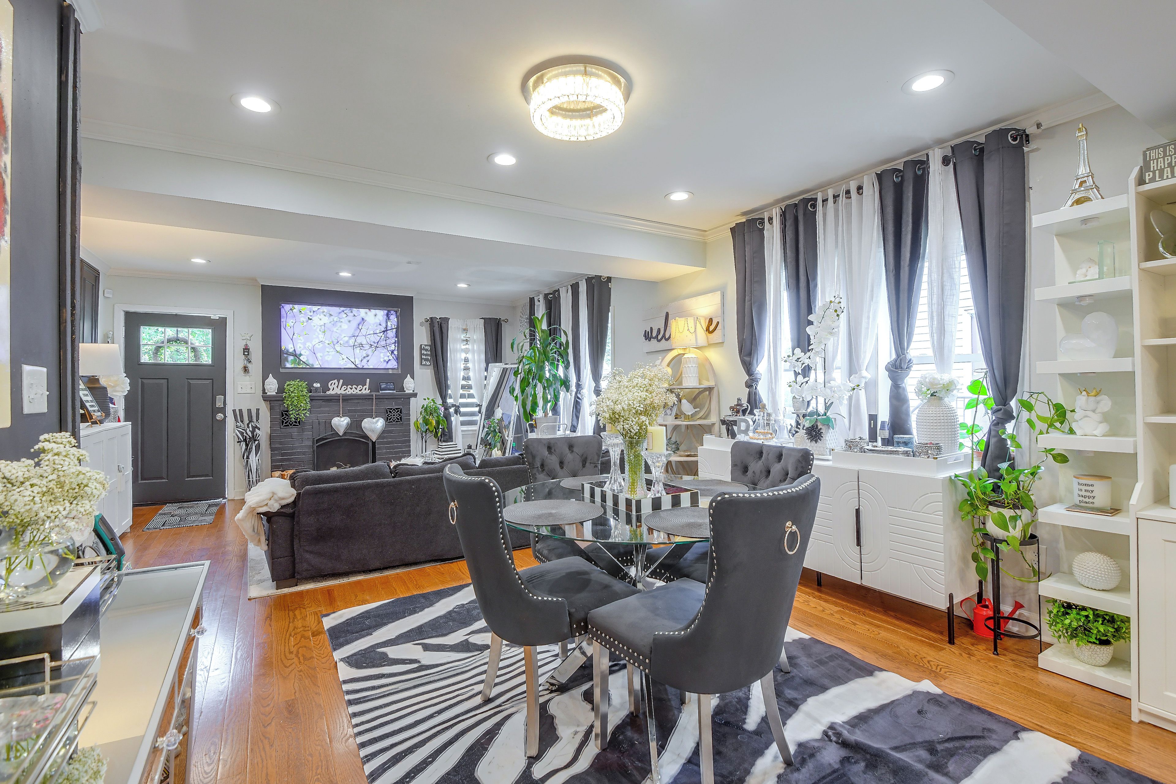 A modern living room with a fireplace, a television, and a dining area with chairs and a table.