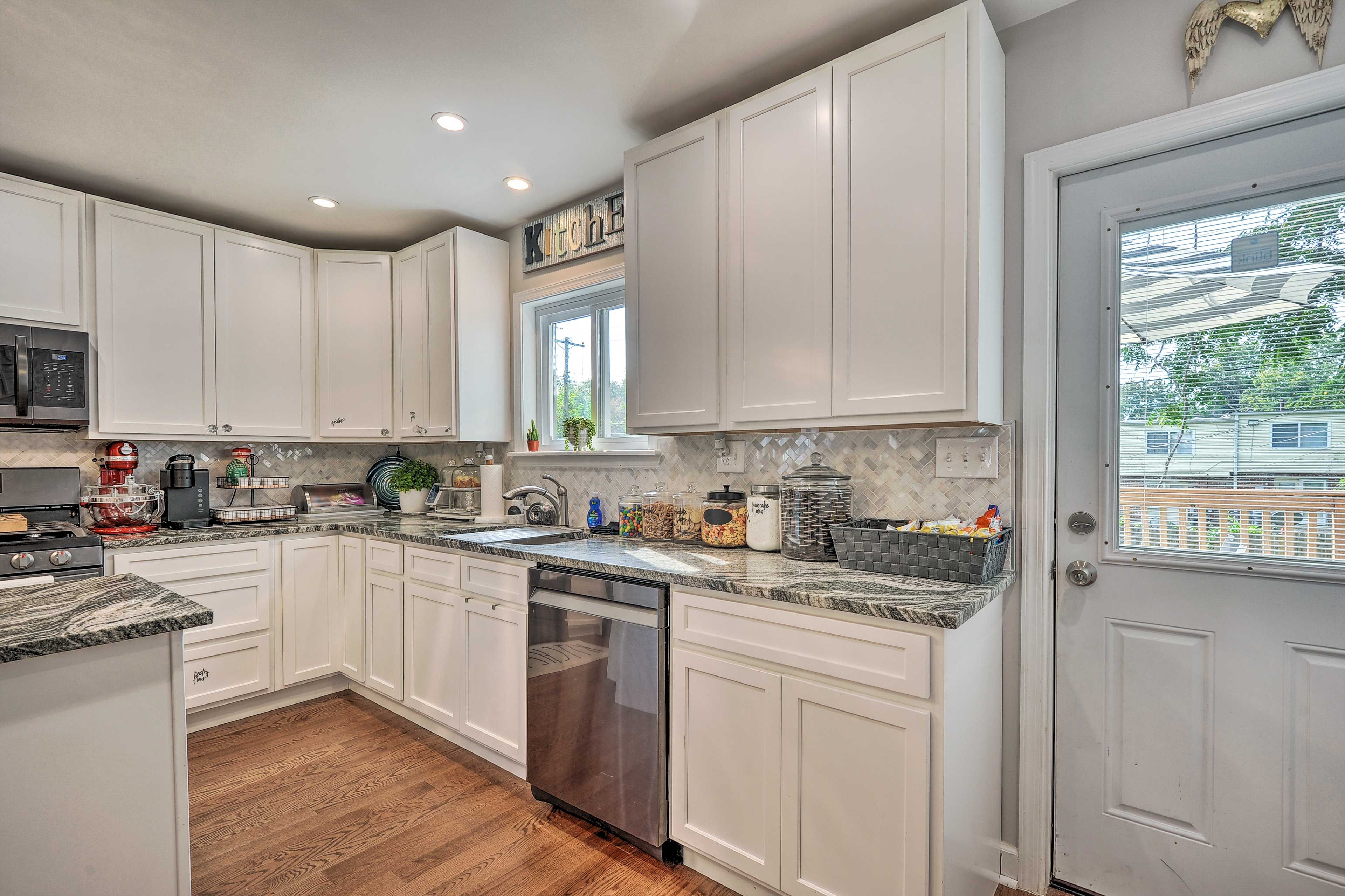A kitchen with white cabinets, a stainless steel dishwasher, and a granite countertop.