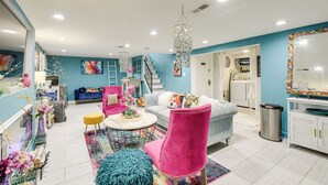A spacious living room with a blue accent wall, a chandelier, a staircase, and a kitchen area. - Butterfly Place-near Johns Hopkins,pimlico,stadium (Baltimore)