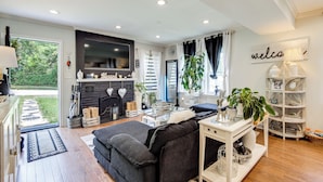 A modern living room with a sofa, TV, fireplace, and a bookshelf. - Butterfly Place-near Johns Hopkins,pimlico,stadium (Baltimore)