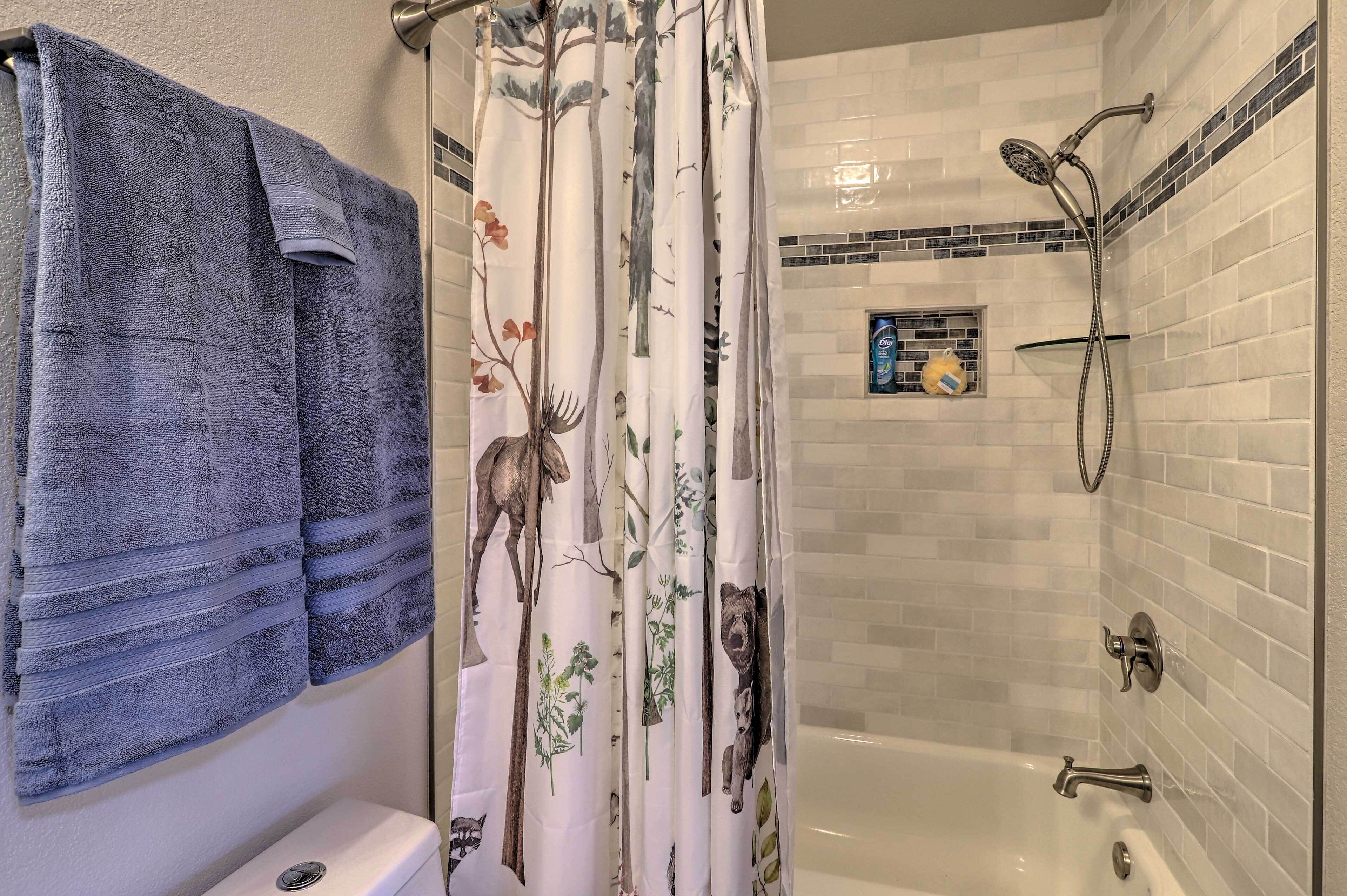 Un bagno con doccia, toilette e un portasciugamani con diversi asciugamani.