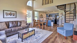 A spacious living room with a leather sofa, a coffee table, and a blue armchair. A dining area with wooden chairs and a kitchen with a modern design and a staircase. - Peaceful Pagosa Springs Escape ~ 2 Mi to Lake (Pagosa Springs)