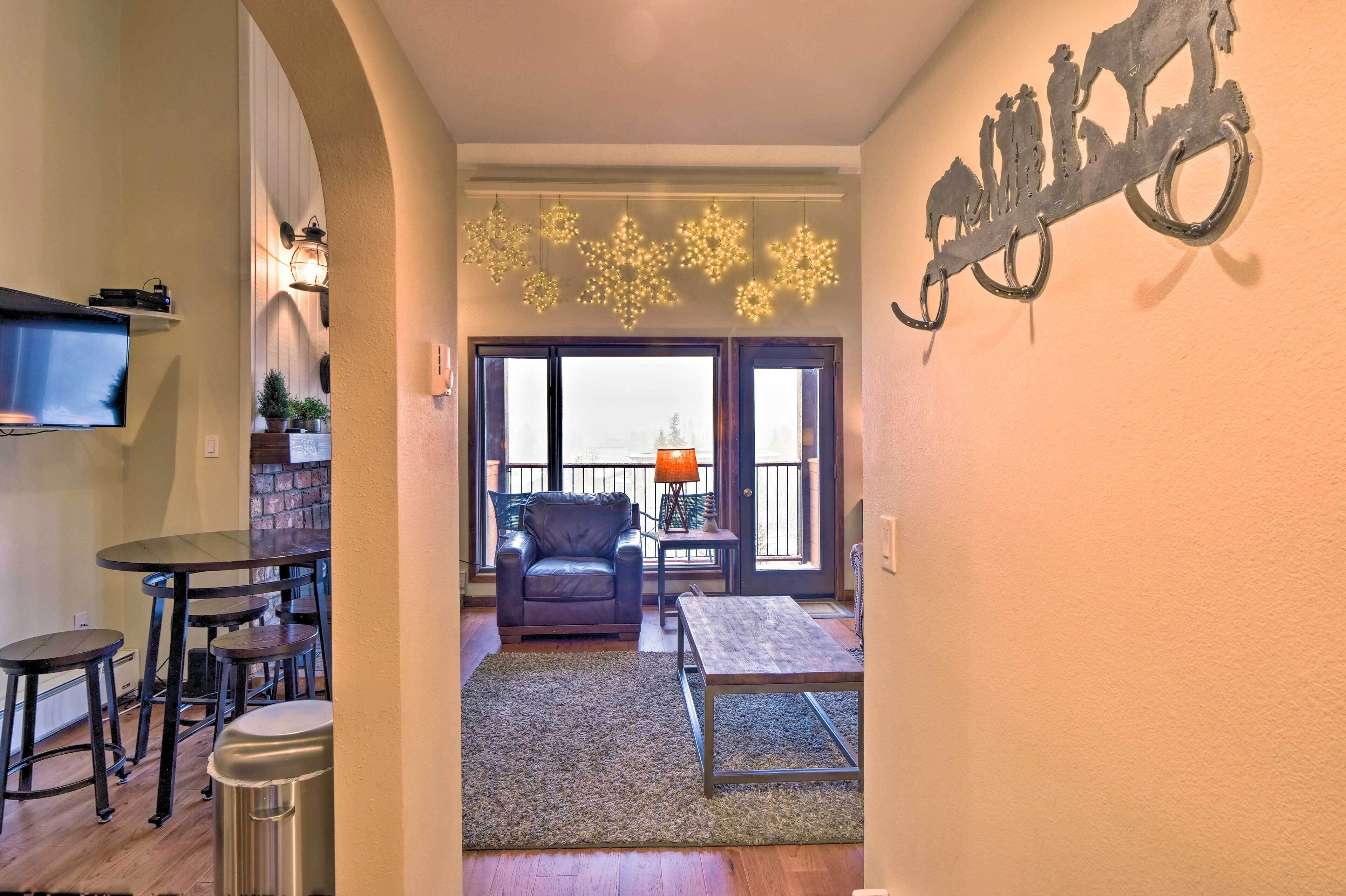 A living room with a fireplace, a television mounted on the wall, and a balcony with a view.